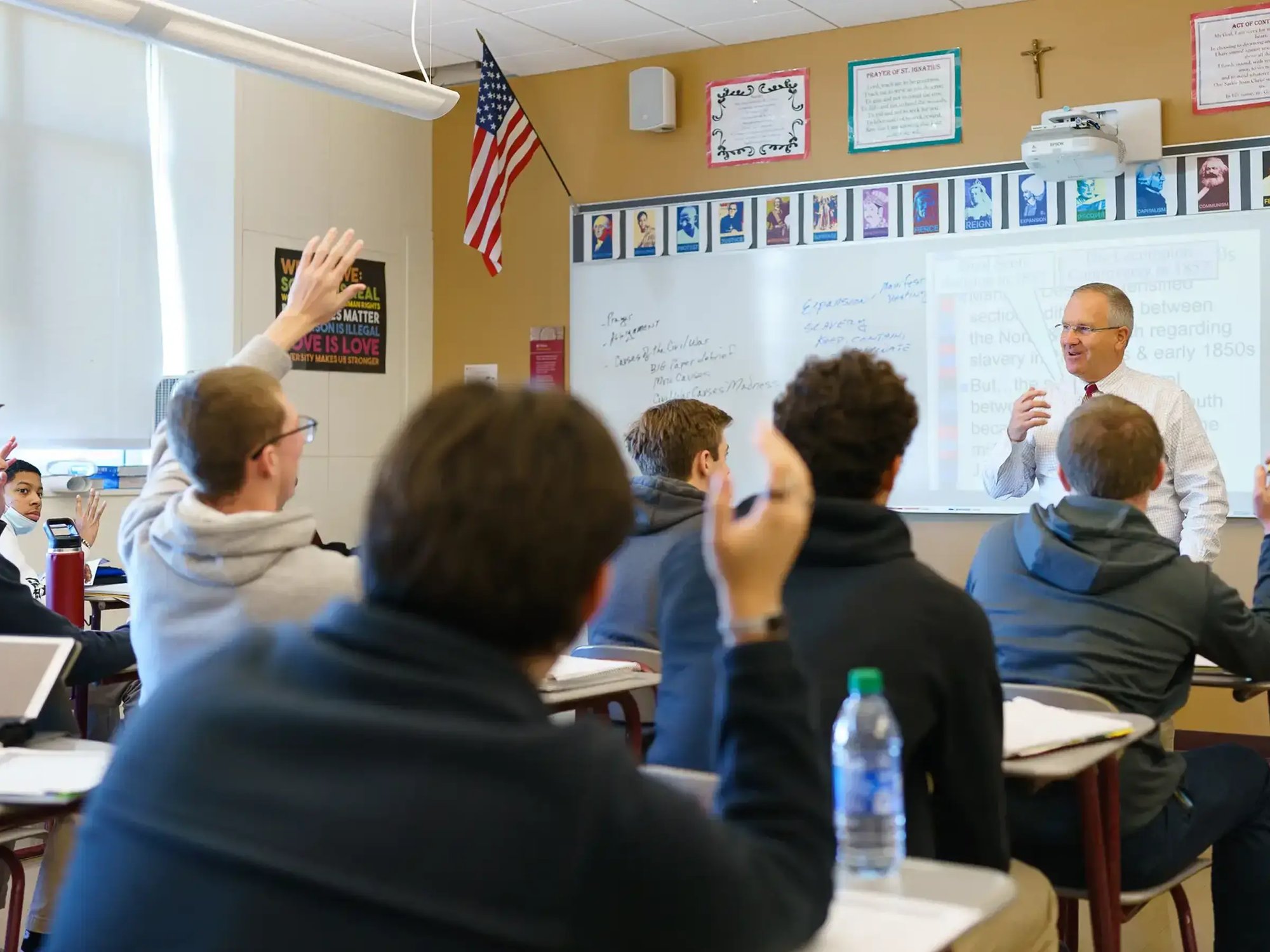 Students raising hands in classroom